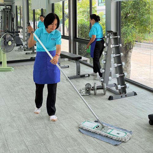 พนักงาน FFC Cleaning ถูพื้นและเช็ดกระจกในห้องฟิตเนสของอาคาร